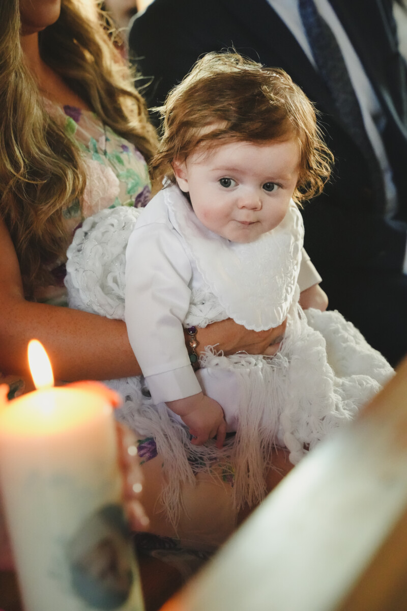 Christening photo of a baby boy seated on his mother’s lap during the ceremony in Ballyheigue, County Kerry – professional Christening photography in Ireland